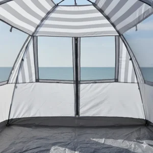 Built-in external sand pockets being filled to keep a sun shelter stable on a breezy UK seaside.