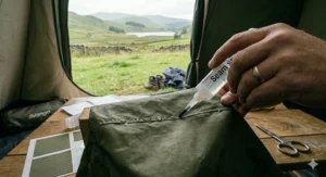 Close-up diagram of a brush applying liquid seam sealer to the internal stitched joints of a tent to prevent water ingress.