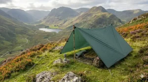 Detailed view of a green camping tarp pitched with a sturdy wooden support pole and tensioned guy lines in the UK highlands.