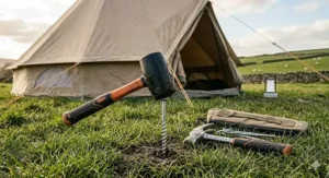 A high-visibility orange-handled mallet resting on a grassy field, making it easy to locate at a busy campsite.