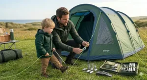 A photorealistic image of a father and young son assembling modular duralumin pole end tips and universal clips on a groundsheet at a UK coastal campsite.