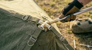 Illustration demonstrating the correct 45-degree angle for driving a tent peg firmly into the ground with a mallet.