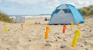 Demonstrating how to use a rubber mallet to gently tap beach tent pegs into hard-packed coastal soil or sand.