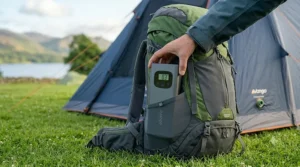 A lightweight, compact rechargeable tent pump being packed into the side pocket of a hiking rucksack.
