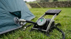 Close-up view of a durable steel foot pump for an air tent, showing the pressure gauge and universal valve attachments.