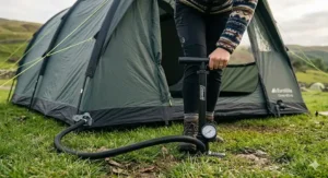 Illustration showing a camper using a manual hand pump to inflate the structural air beams of a modern inflatable tent.