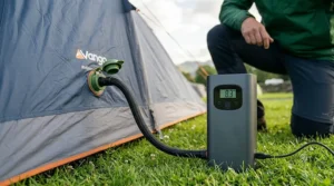 Close-up of a compact rechargeable tent pump showing the digital pressure gauge screen and USB-C charging port.