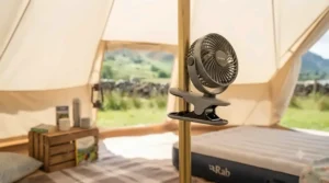 A portable clip-on fan securely attached to a tent pole, providing airflow inside a tent.