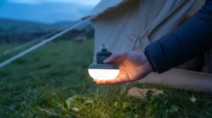 A compact, lightweight tent light sitting in a palm, showing its portable size for backpackers and hikers.