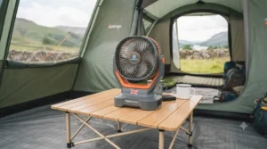 Compact, battery-operated tent fan sitting on a small camping table for easy airflow.