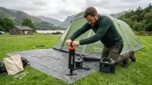 A camper using a manual double-action hand pump to inflate a tent, showcasing the physical effort required.