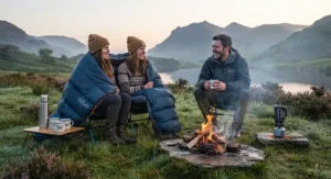 Campers relaxing by a campfire using an unzipped summer sleeping bag as an outdoor blanket.