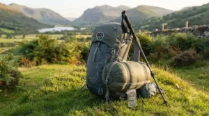 A lightweight sleeping bag packed into a compression sack, attached to a hiking rucksack for wild camping.