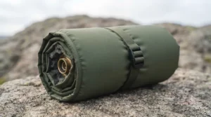 A lightweight self-inflating sleeping mat compressed inside its stuff sack next to a standard 1-litre water bottle for scale.
