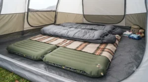 A thick double self-inflating sleeping mat laid out inside a spacious family tunnel tent at a Cornish campsite.