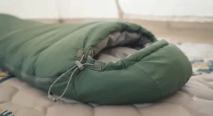 A hooded zip-together sleeping bag laid flat to show the drawcord hood and shoulder baffle.