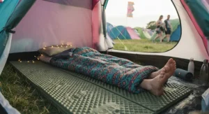 A thick foam sleeping mat set up inside a festival tent to provide extra comfort and padding on hard ground.