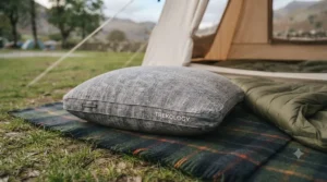 A compact memory foam camping pillow rolled up tightly inside its waterproof carry bag for easy backpacking.