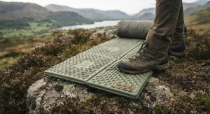 A rugged, tear-resistant foam sleeping mat laid out on rocky terrain during an outdoor hiking excursion.