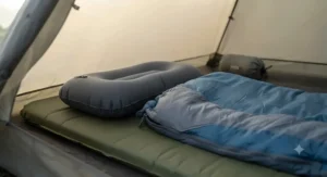 An organised wild camping sleep setup featuring an inflatable pillow, insulated sleeping mat, and down sleeping bag inside a compact backpacking tent.