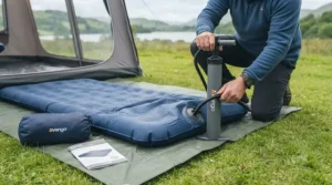 Campers using a portable foot pump to inflate a double air bed for camping.