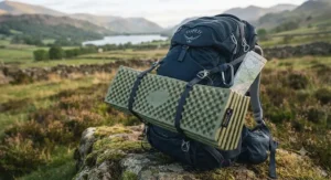 A compact, foldable foam sleeping mat securely strapped to the outside of a hiking rucksack for a weekend trek.
