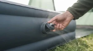 Close-up of a wide-mouth quick-deflate valve on a camping air mattress being opened to release air.