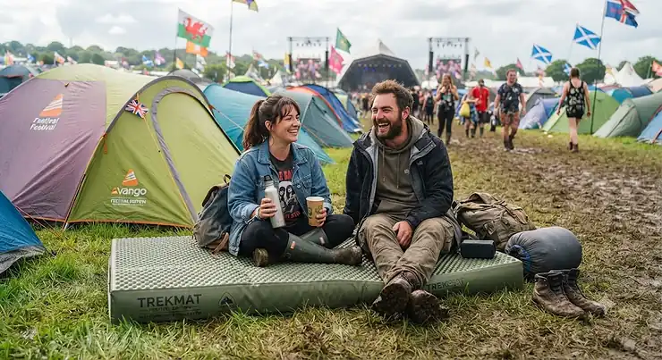 A festival-goer relaxing on a comfortable roll mat at a muddy British music festival campsite. roll mat for festivals